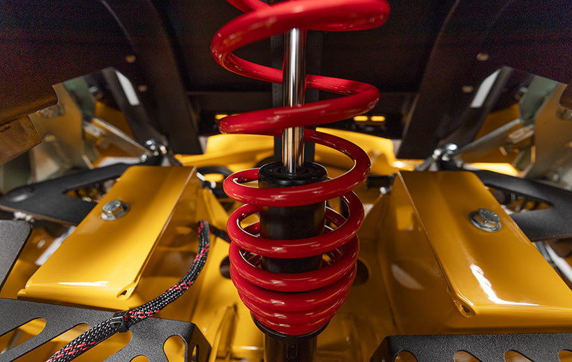 Close-up of a red shock absorber on a yellow vehicle