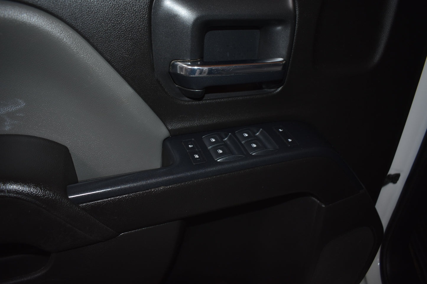 Close-up of a car door panel with controls and handle.