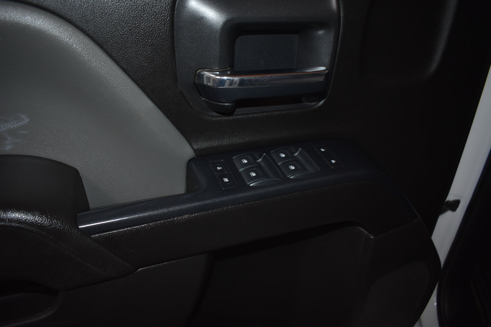 Close-up of a car door panel with controls and handle.