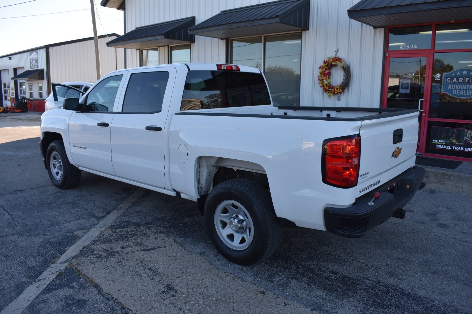 White pickup truck parked in front of a building with a wreath on the door.