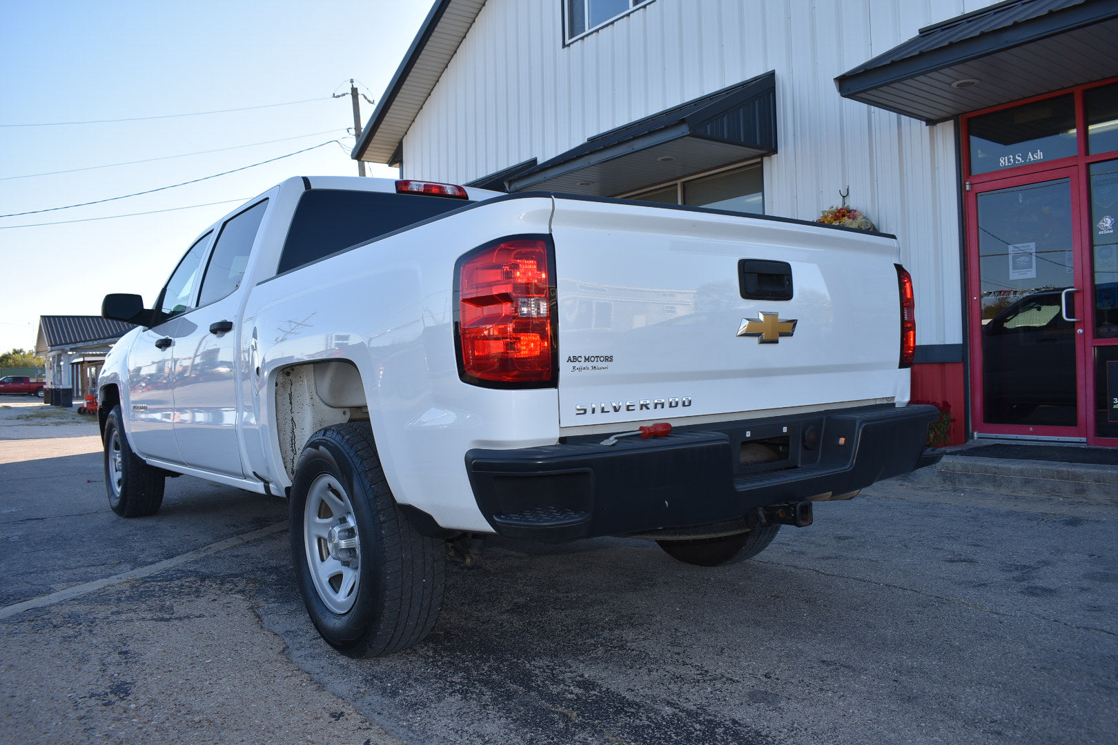White Chevrolet Silverado truck parked in front of a building with a red door.