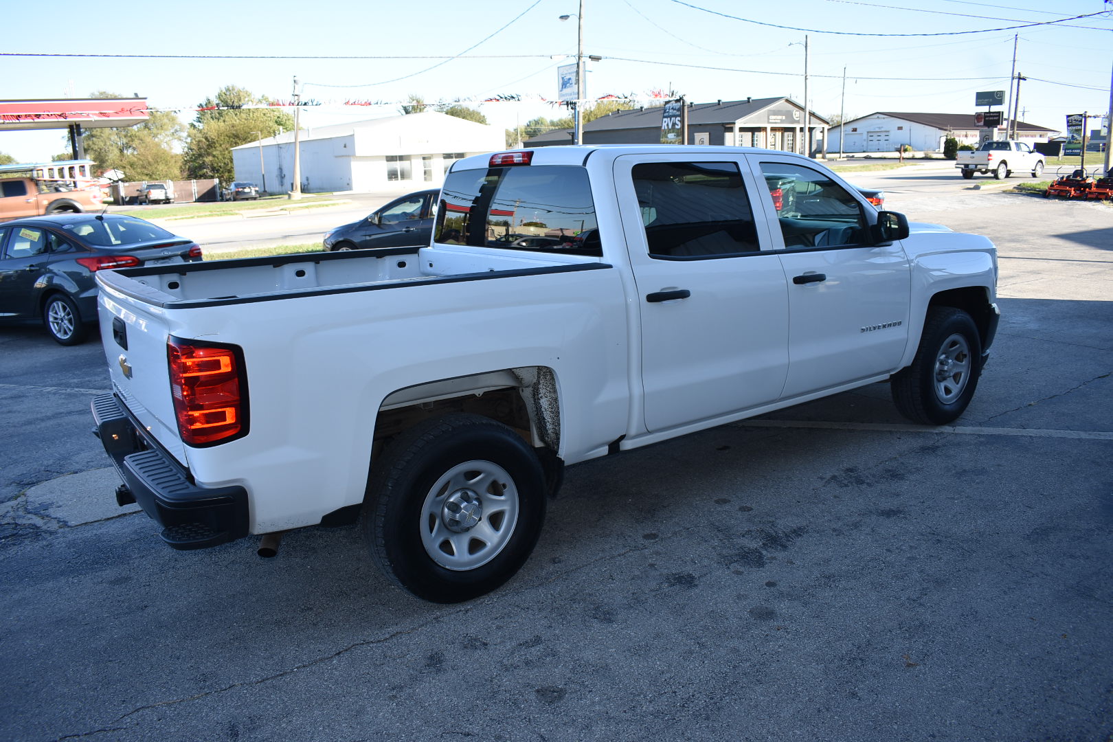 White pickup truck parked in a lot with buildings and cars in the background