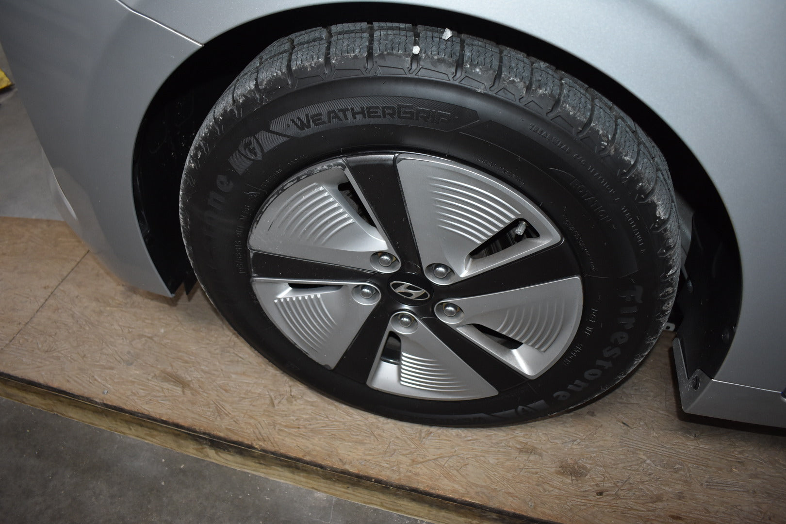 Car tire with 'WeatherTech' branding on a wooden surface