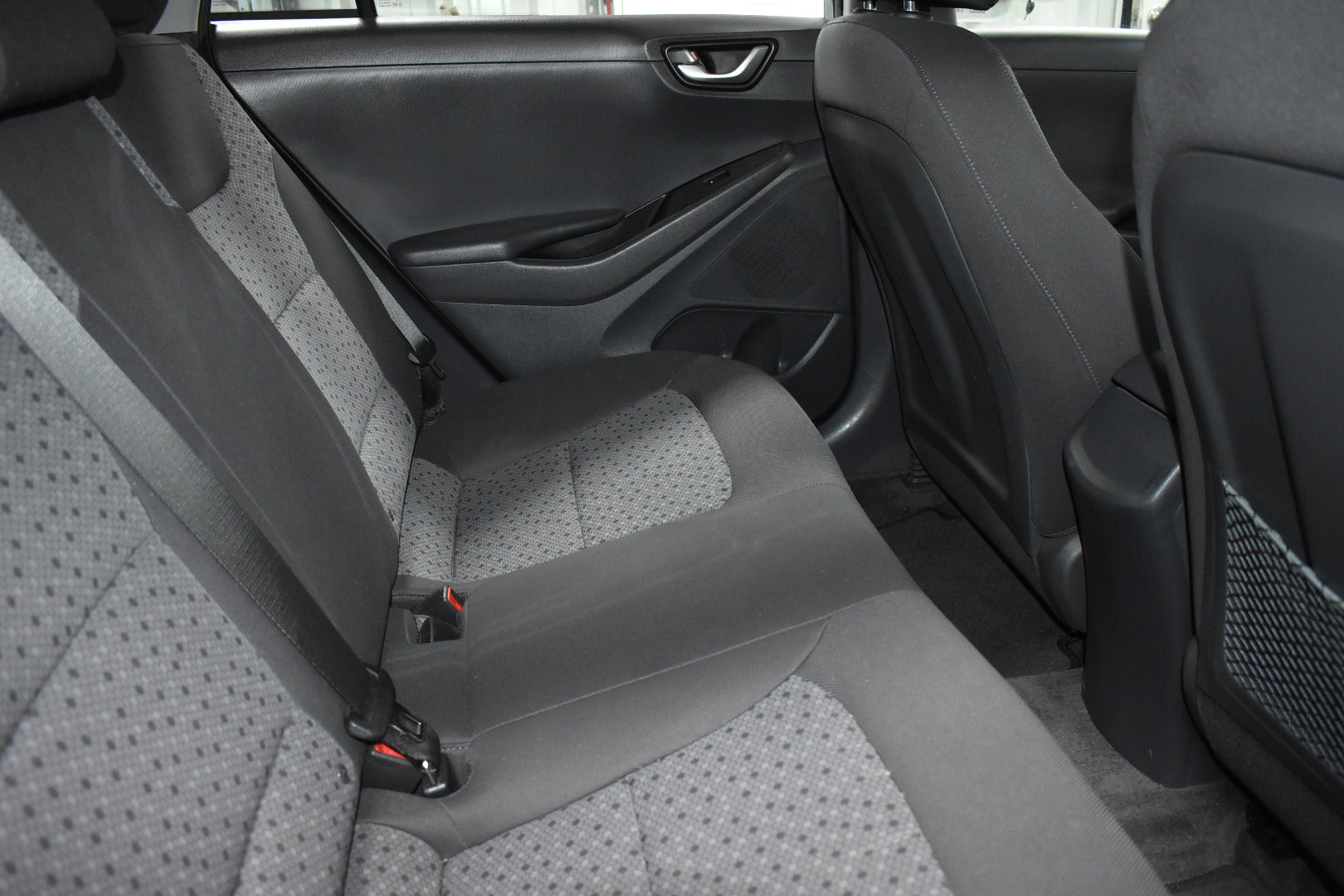 Gray car interior with visible seat belts and door panel.