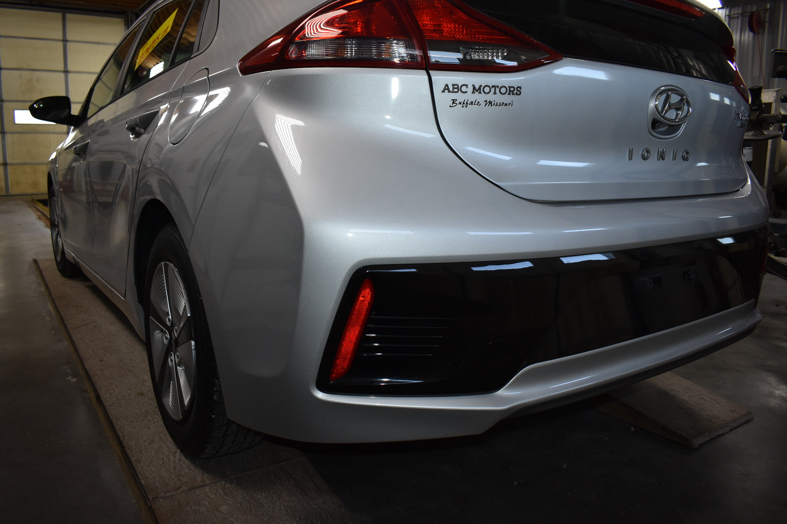 White Hyundai Ioniq electric vehicle in a garage with 'ABC MOTORS' branding.