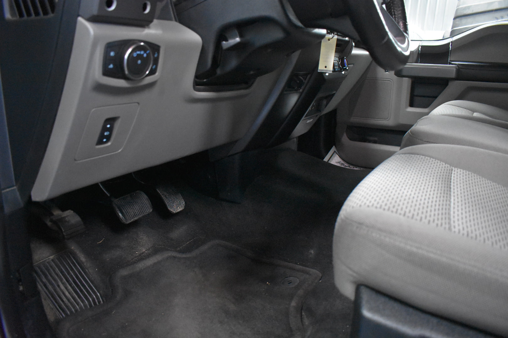 Close-up of a vehicle's interior with pedals and dashboard.