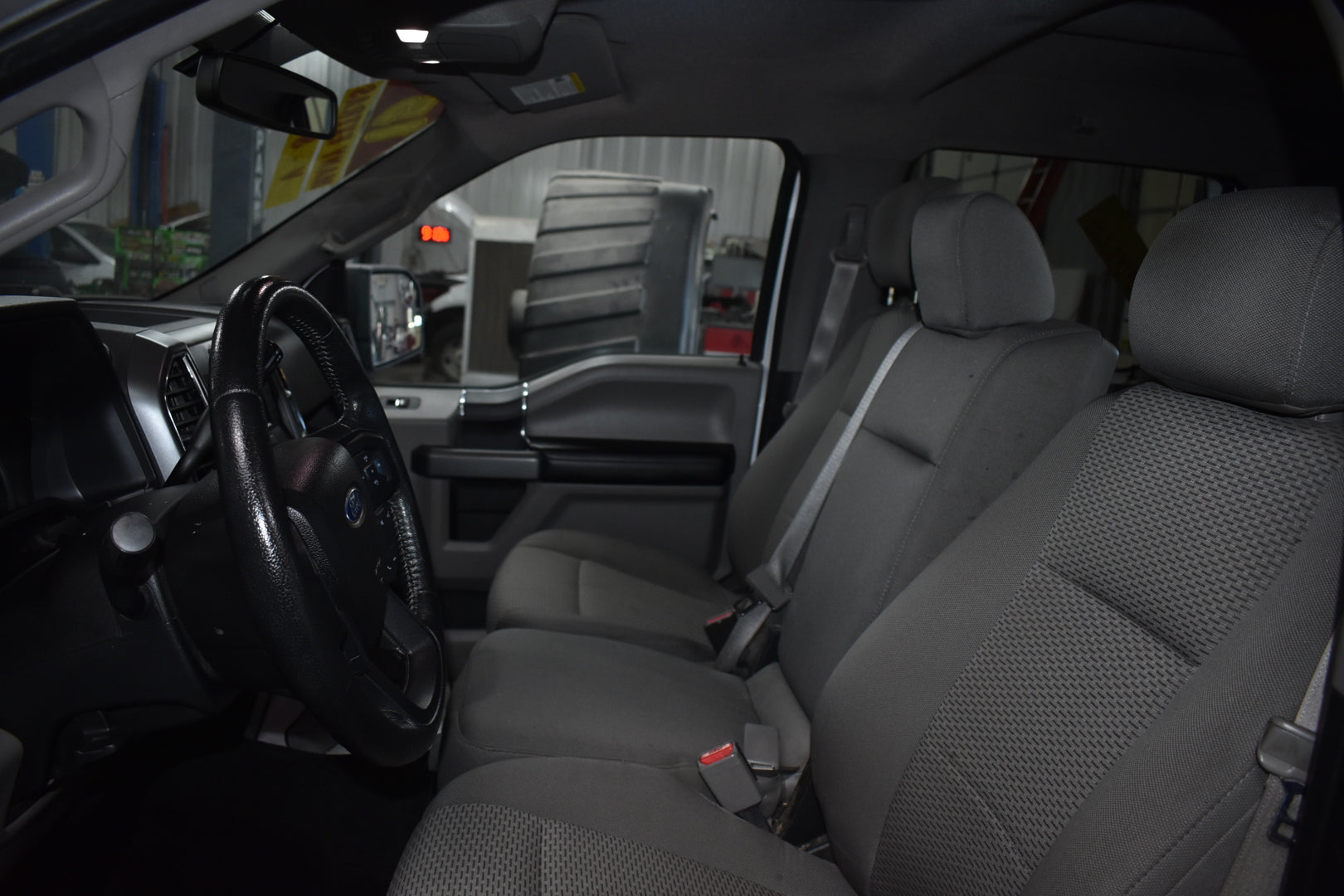 Gray car interior with steering wheel and seats in a showroom setting