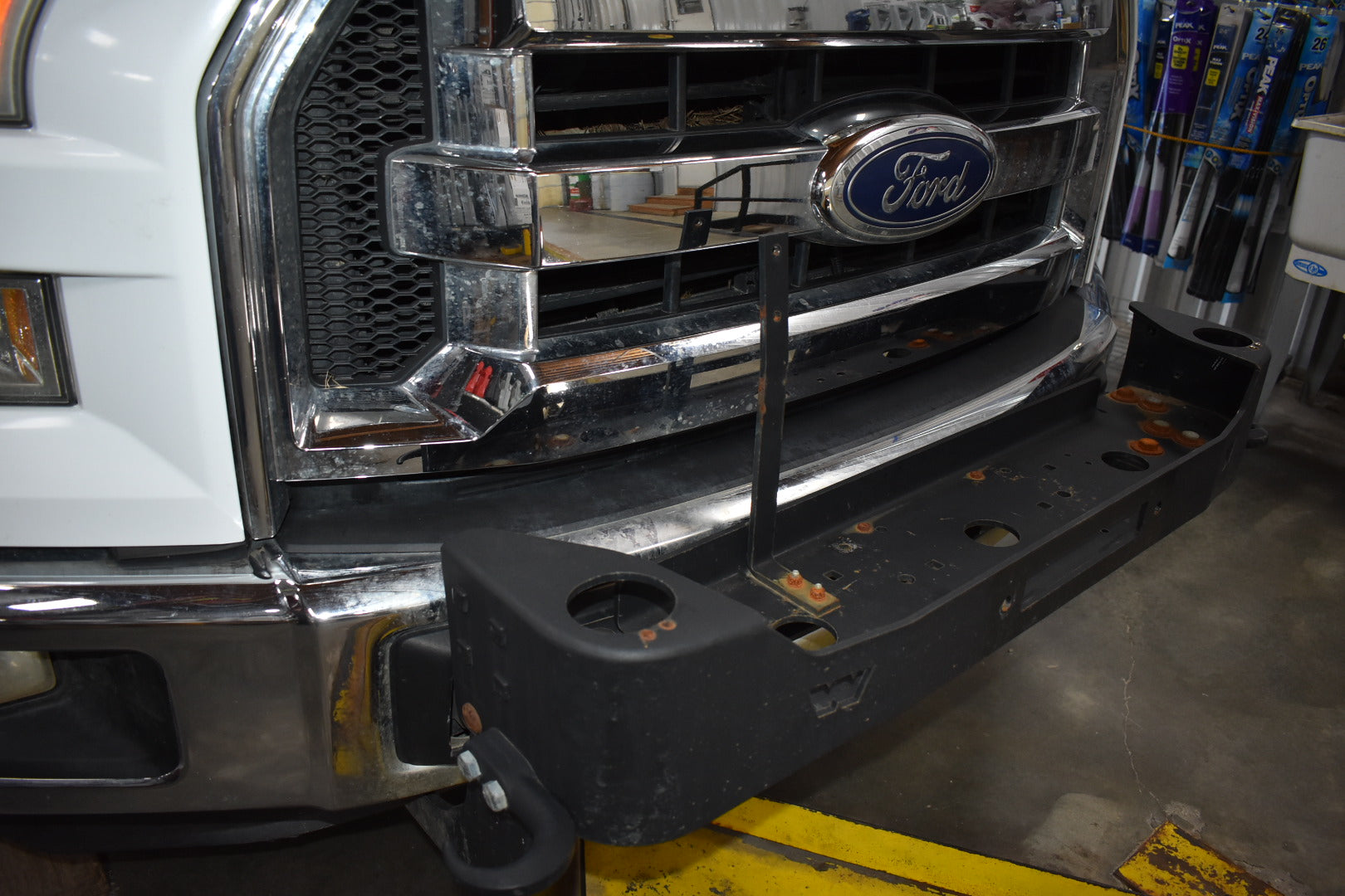 Ford truck with a damaged front bumper in a garage setting
