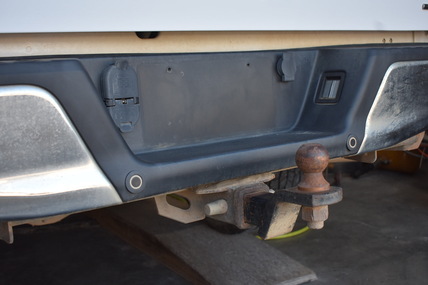 Close-up of a vehicle's hitch receiver with a ball attachment on a trailer.