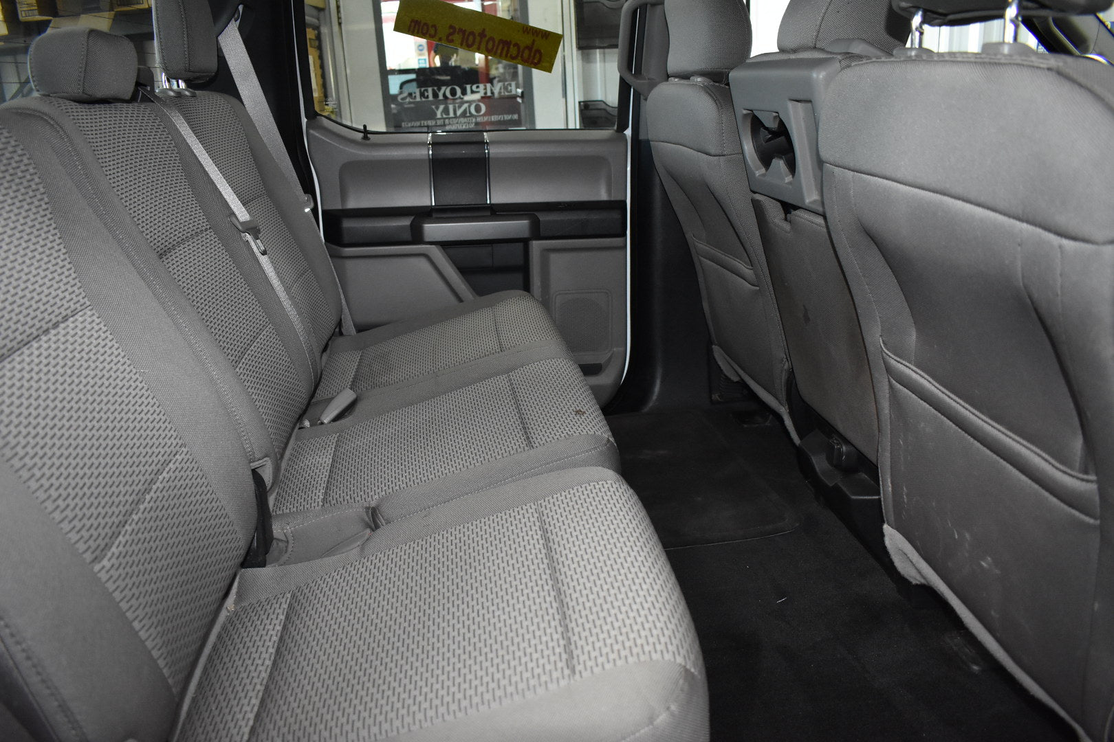 Gray car interior with visible seat belts and door panels.