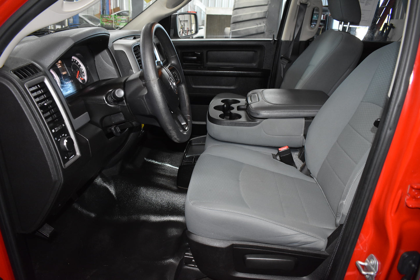 Car interior with gray seats and dashboard, showing a clear view of the steering wheel and cup holders.