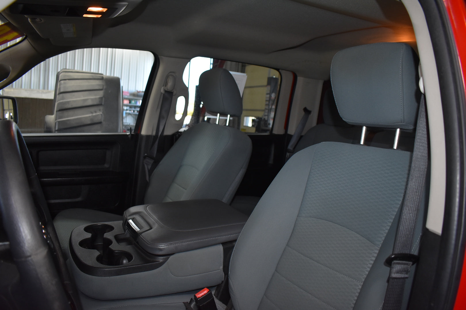 Car interior with gray seats and cup holder, showing a blurred outdoor background.