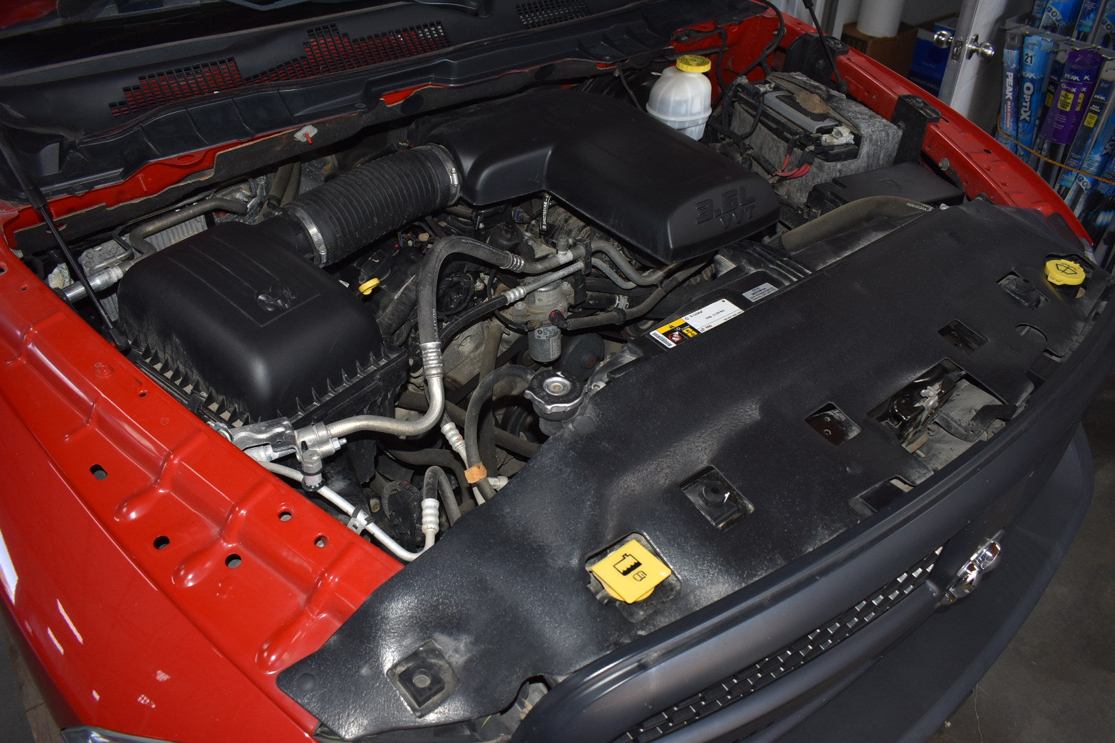 Open hood of a red car revealing the engine compartment.