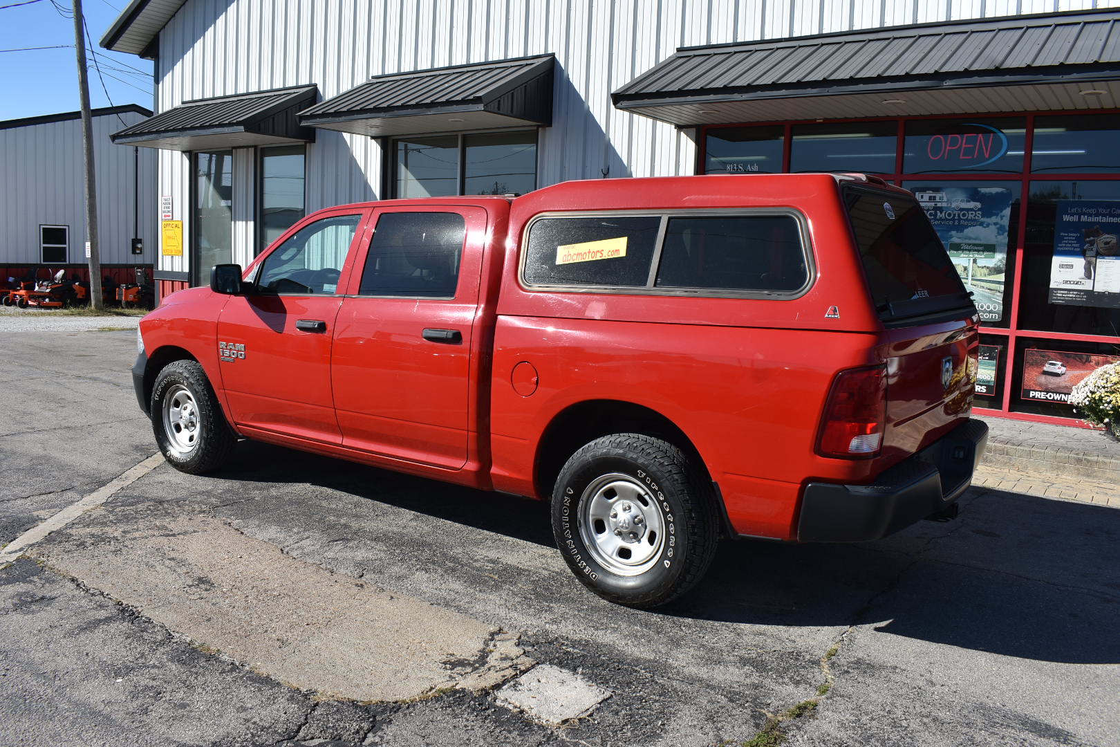 Red pickup truck with a canopy parked in front of a building