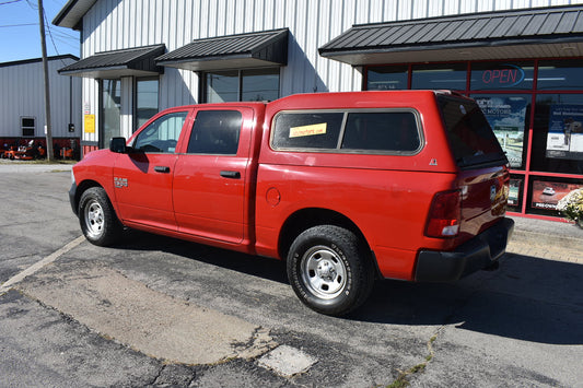 Red pickup truck with a canopy parked in front of a building