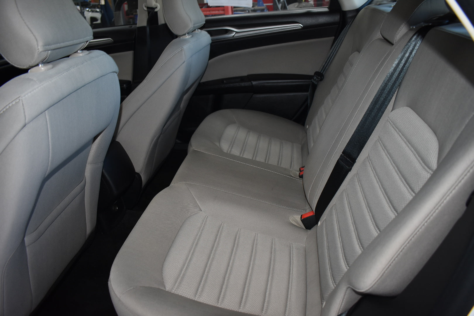 Beige car seats with a visible seat belt in a vehicle interior.