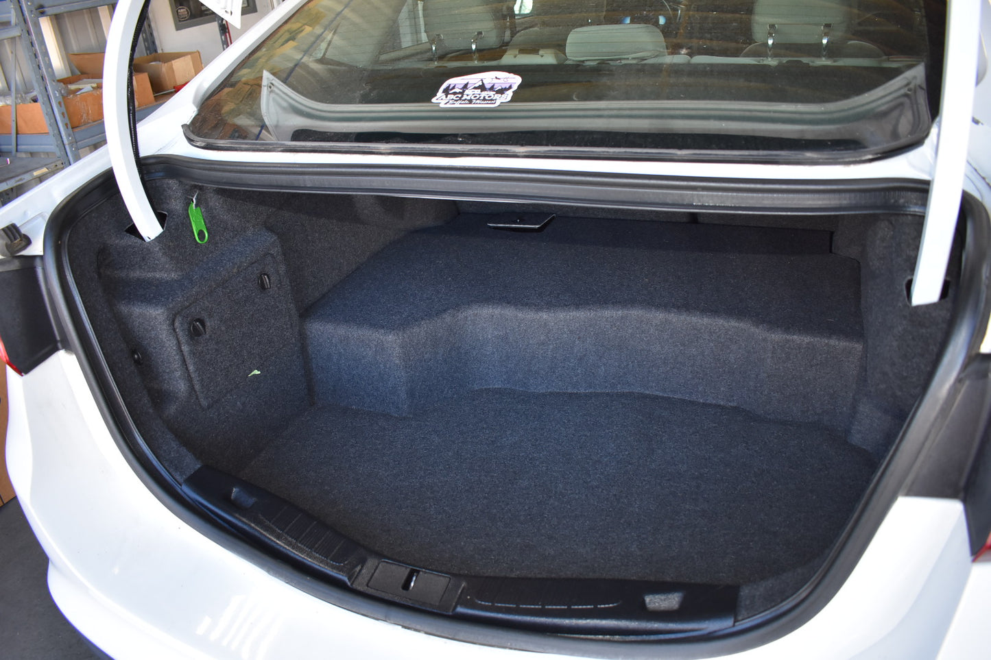 Open car trunk with blue carpeting and a visible brand logo on the glass.