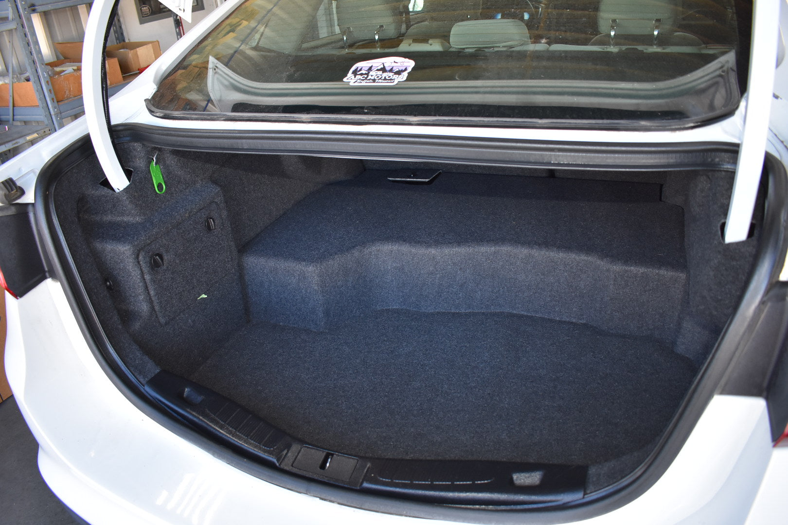 Open car trunk with blue carpeting and a visible brand logo on the glass.