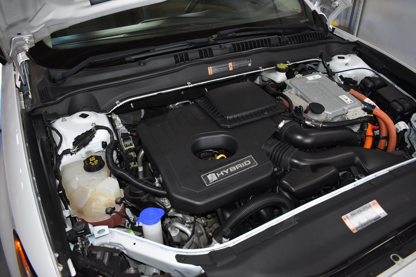 Car engine compartment with 'Hybrid' label open hood