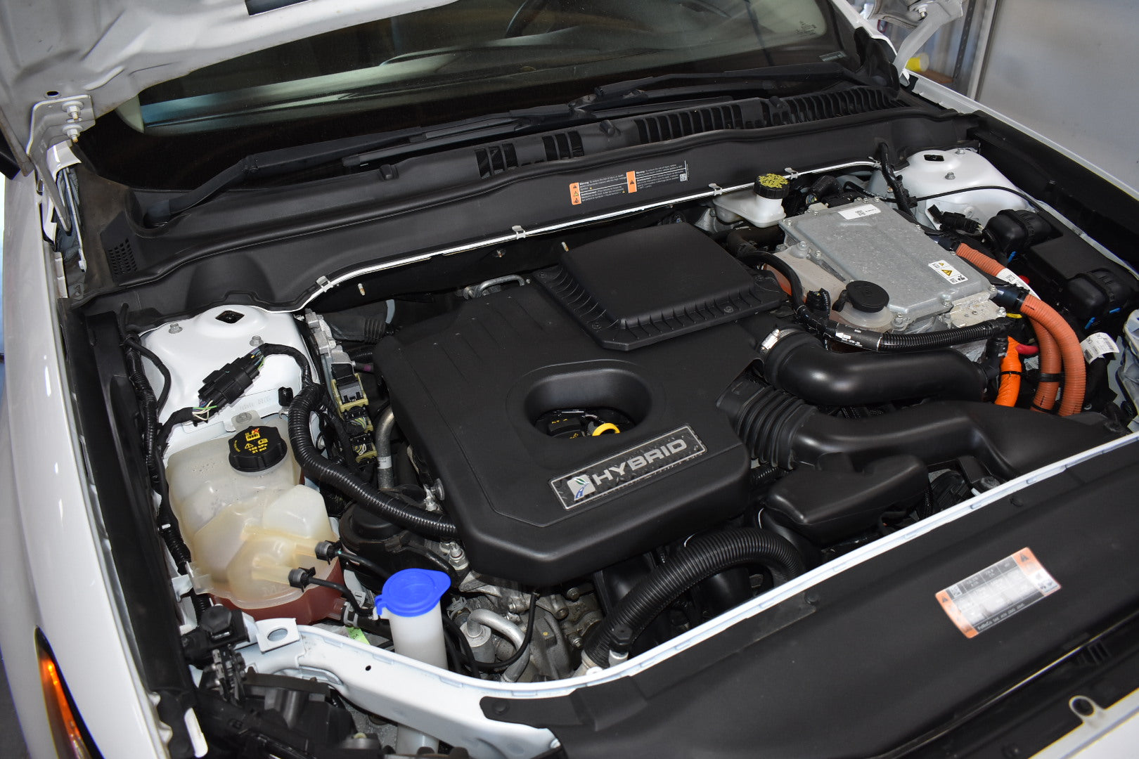 Car engine compartment with 'Hybrid' label open hood