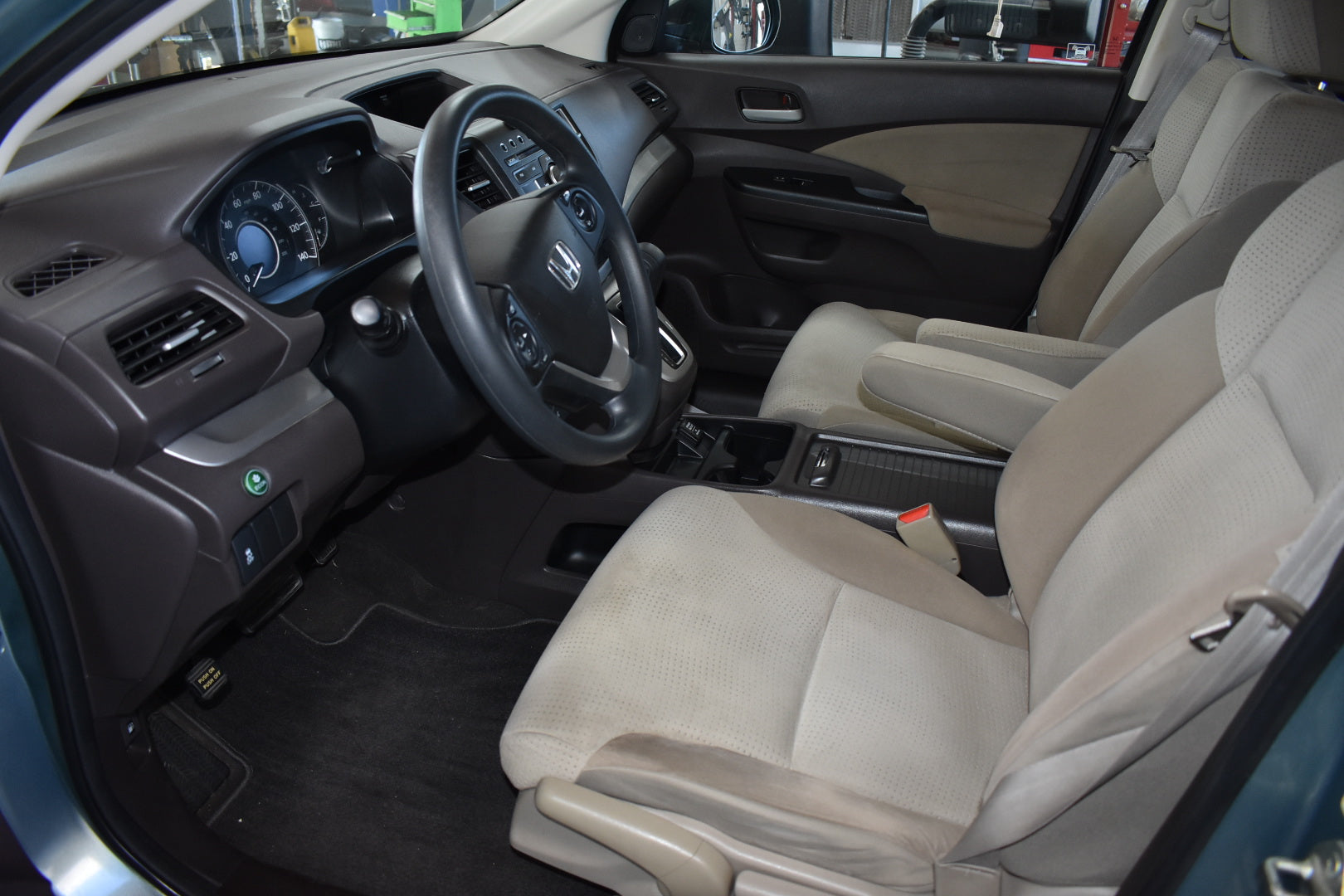Car interior with beige seats and dashboard, showing steering wheel and controls.