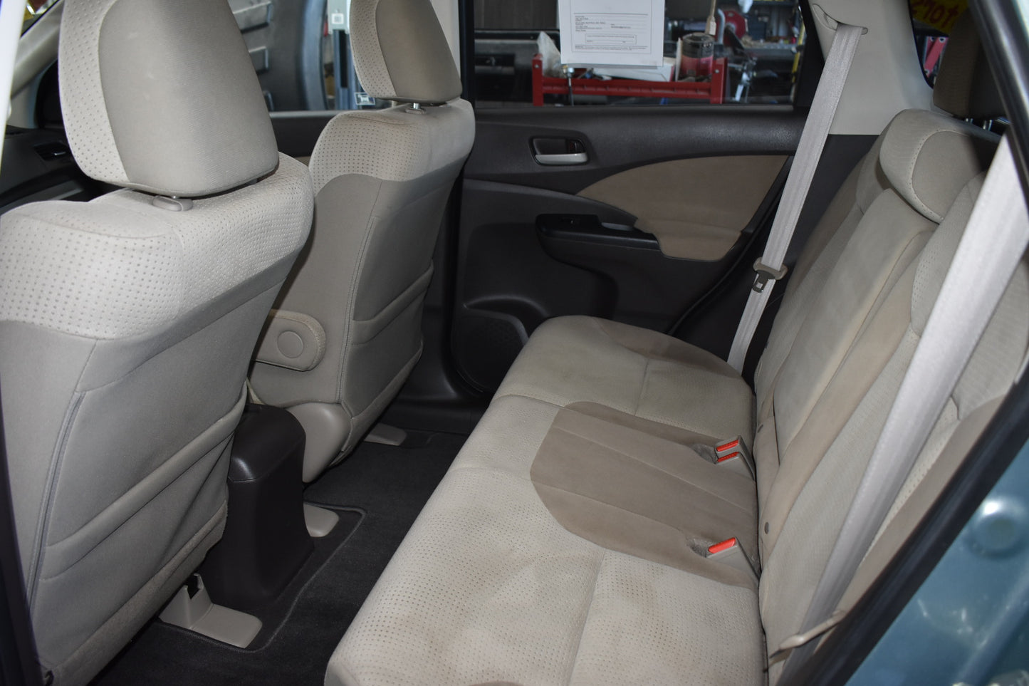 Back seat interior of a vehicle with beige seats and visible car parts.