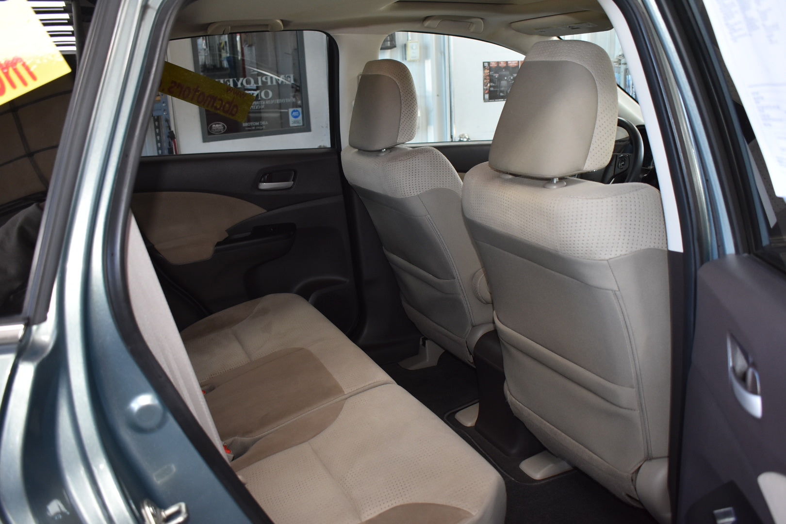 Car interior with beige seats and open door showing a dealership background