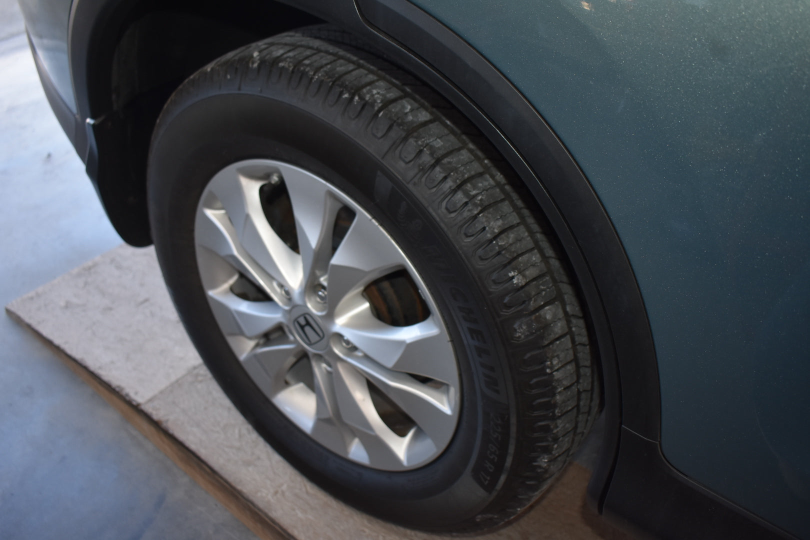 Close-up of a car tire with a visible brand logo on a gray surface.