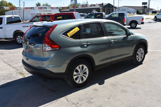 Silver Honda CR-V parked in a lot with other vehicles and buildings in the background