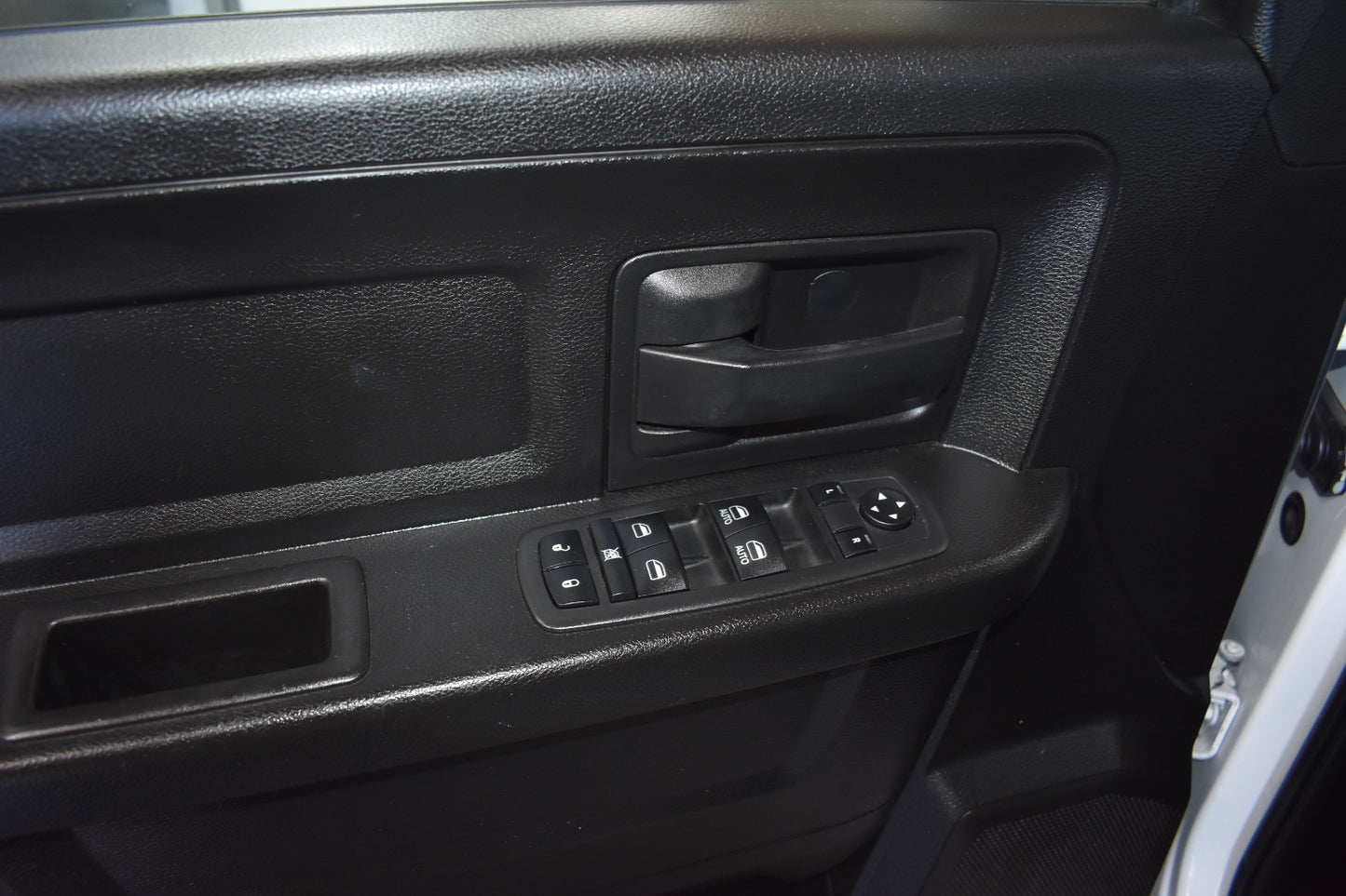 Close-up of a car door panel with controls and handle.