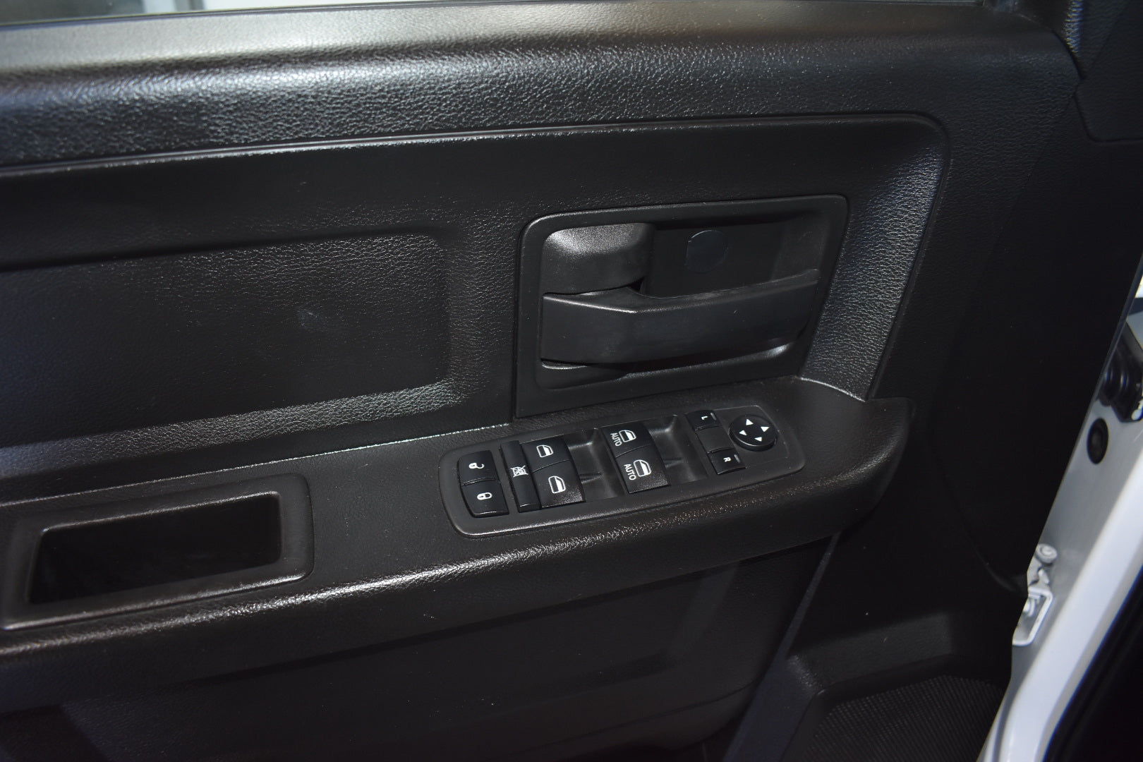 Close-up of a car door panel with controls and handle.