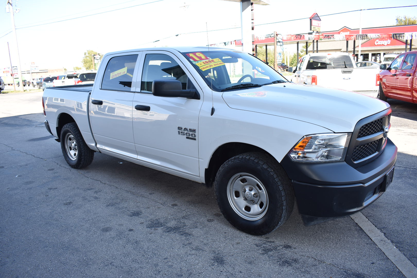 White pickup truck parked on a street with a gas station in the background