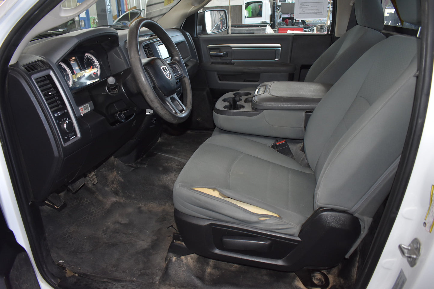 Car interior with gray seats and dashboard, showing the steering wheel and door panel.