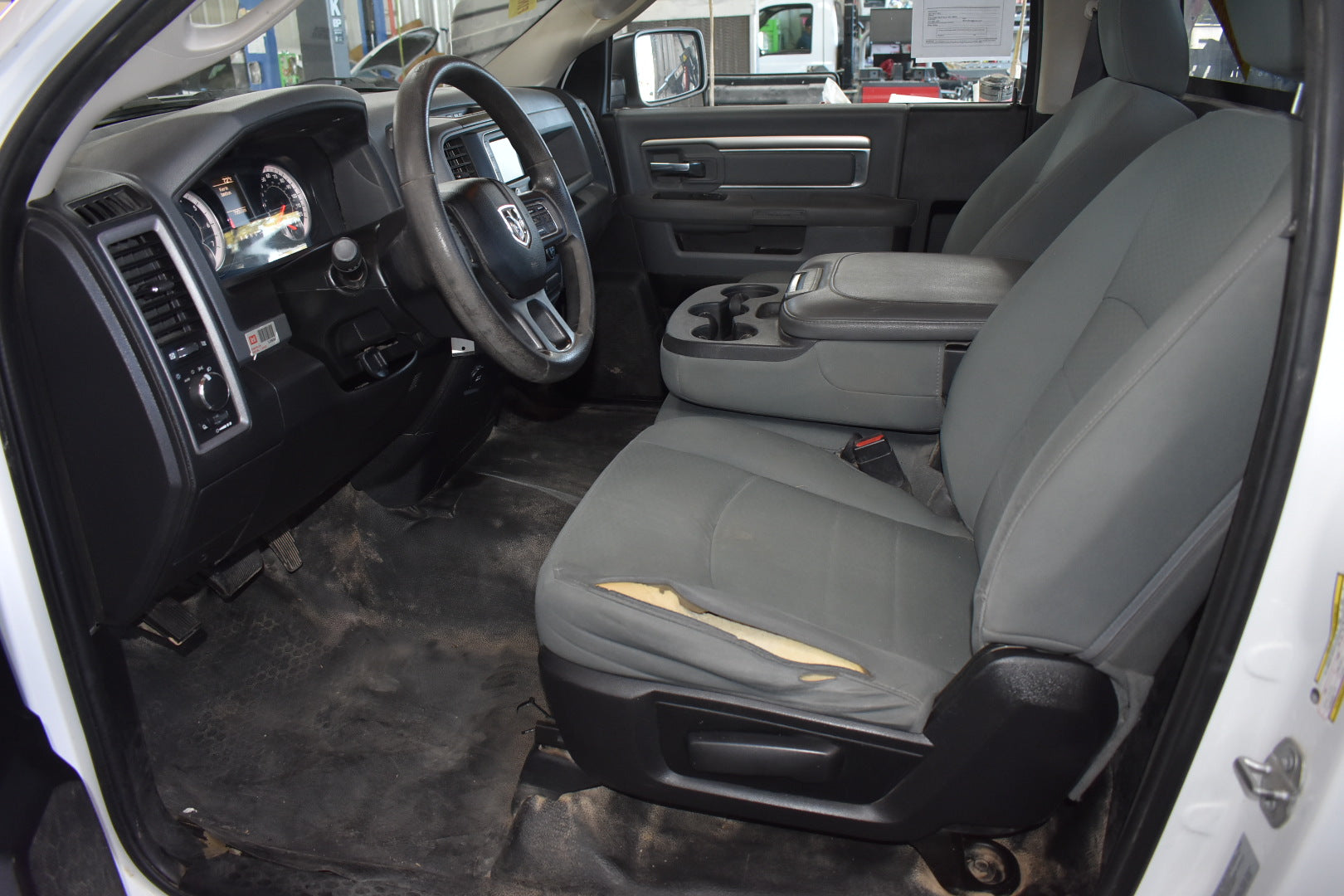 Car interior with gray seats and dashboard, showing the steering wheel and door panel.