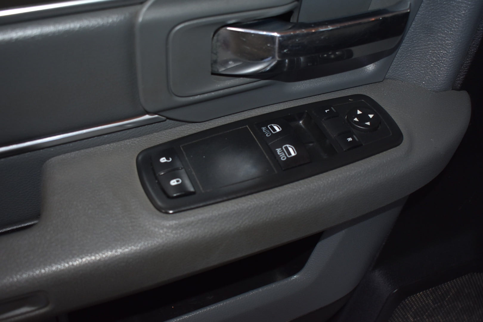 Car interior door panel with window and mirror controls.
