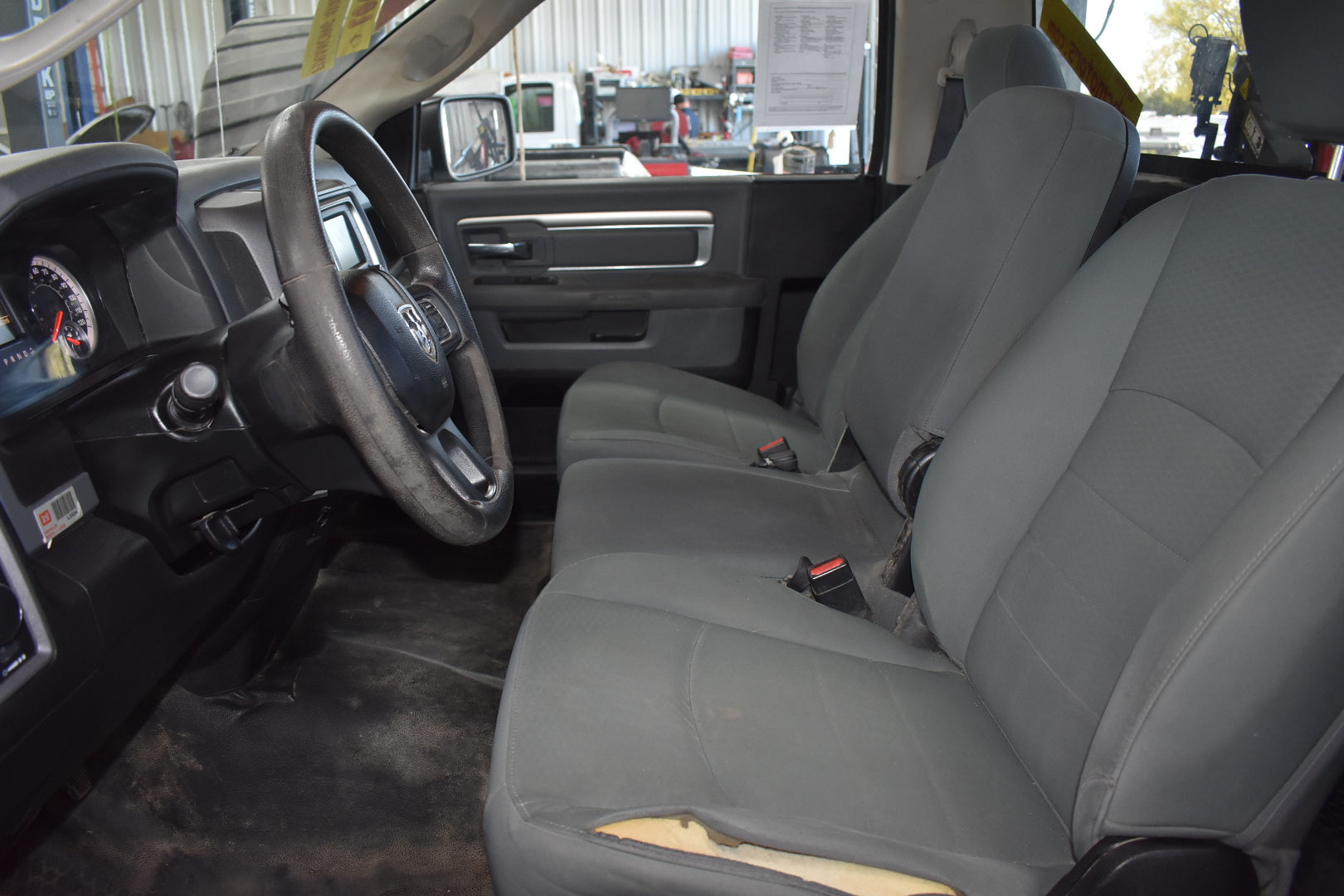 Gray interior of a vehicle with steering wheel and seats.