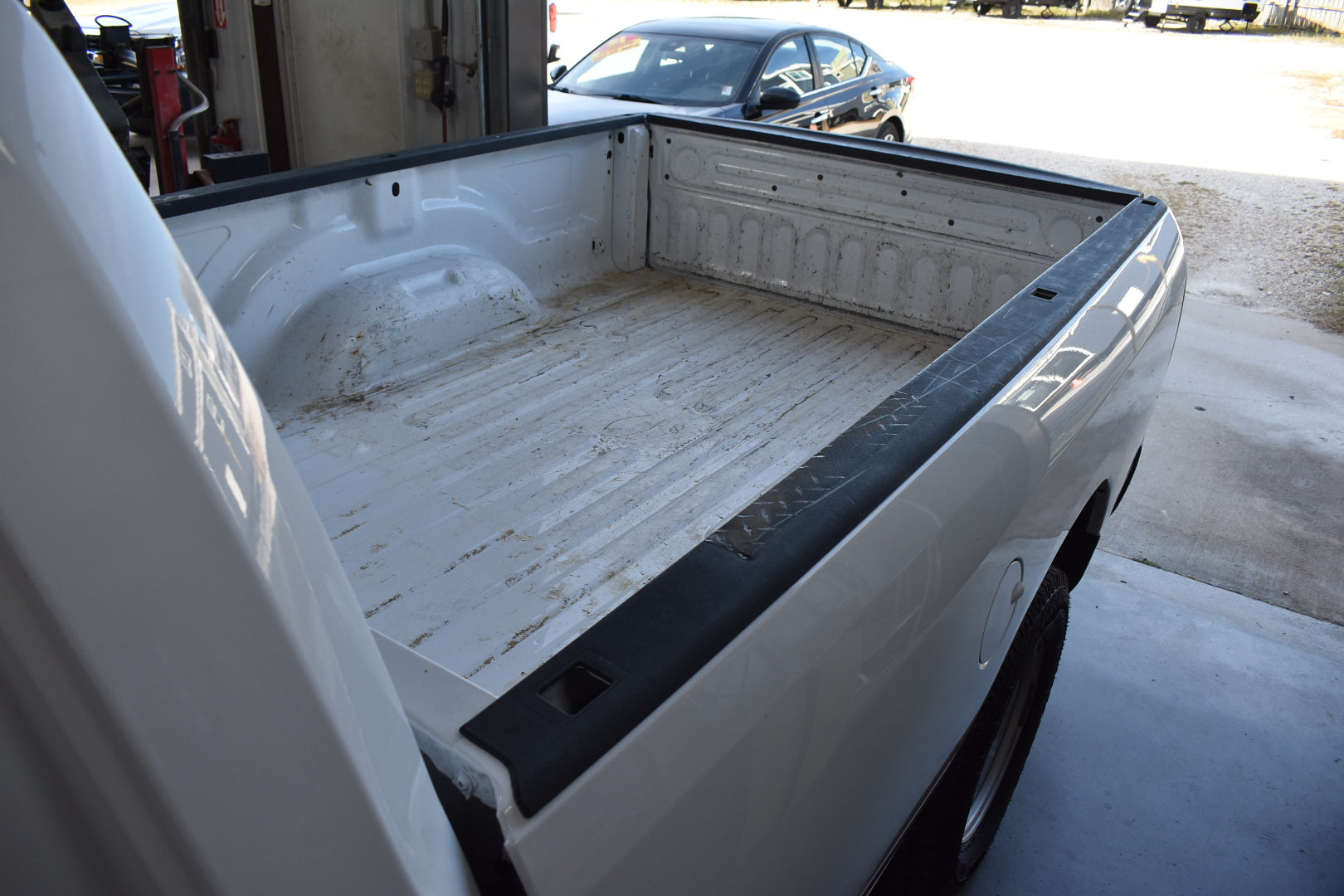 Close-up of a white truck bed with black trim in a garage setting