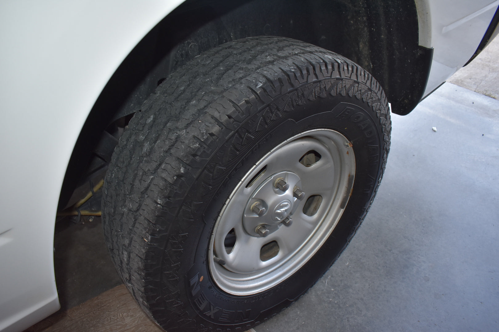 Tire of a vehicle with a white rim on a concrete surface