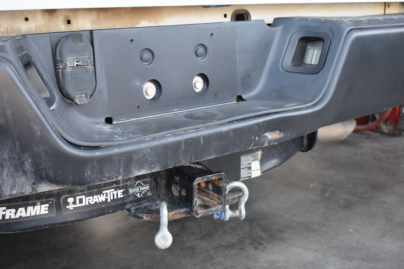 Close-up of a vehicle bumper with 'Draw-Tite' branding on a concrete floor.