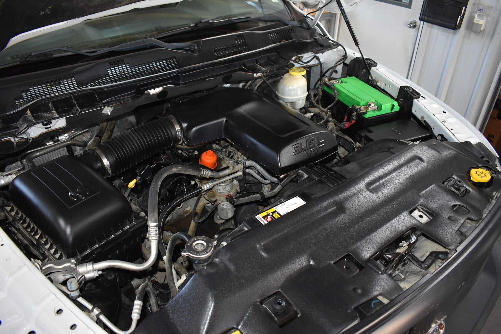 Open car hood revealing the engine compartment with various components.