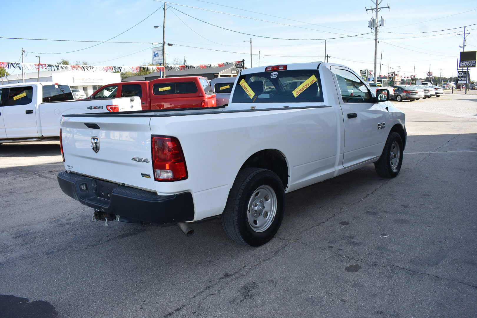 White pickup truck in a lot with other vehicles and signs in the background