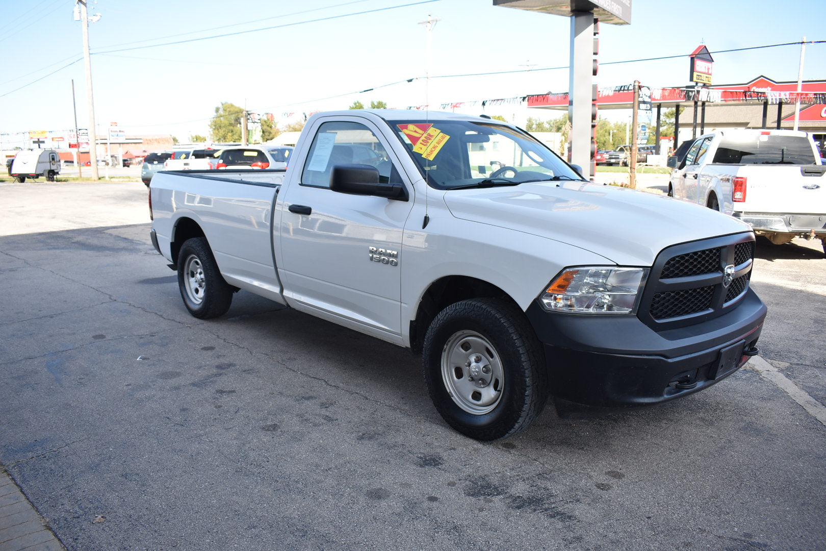 White pickup truck with a sale tag on a gas station lot