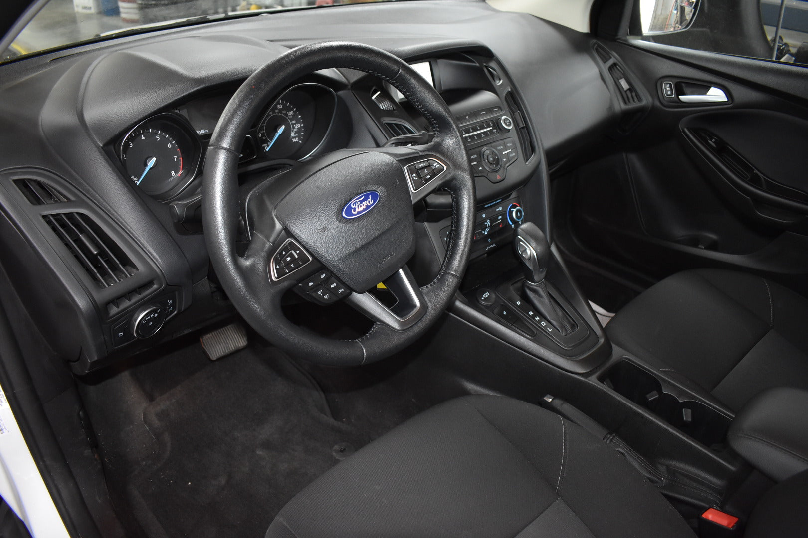 Car interior with steering wheel and dashboard, featuring a Ford logo.