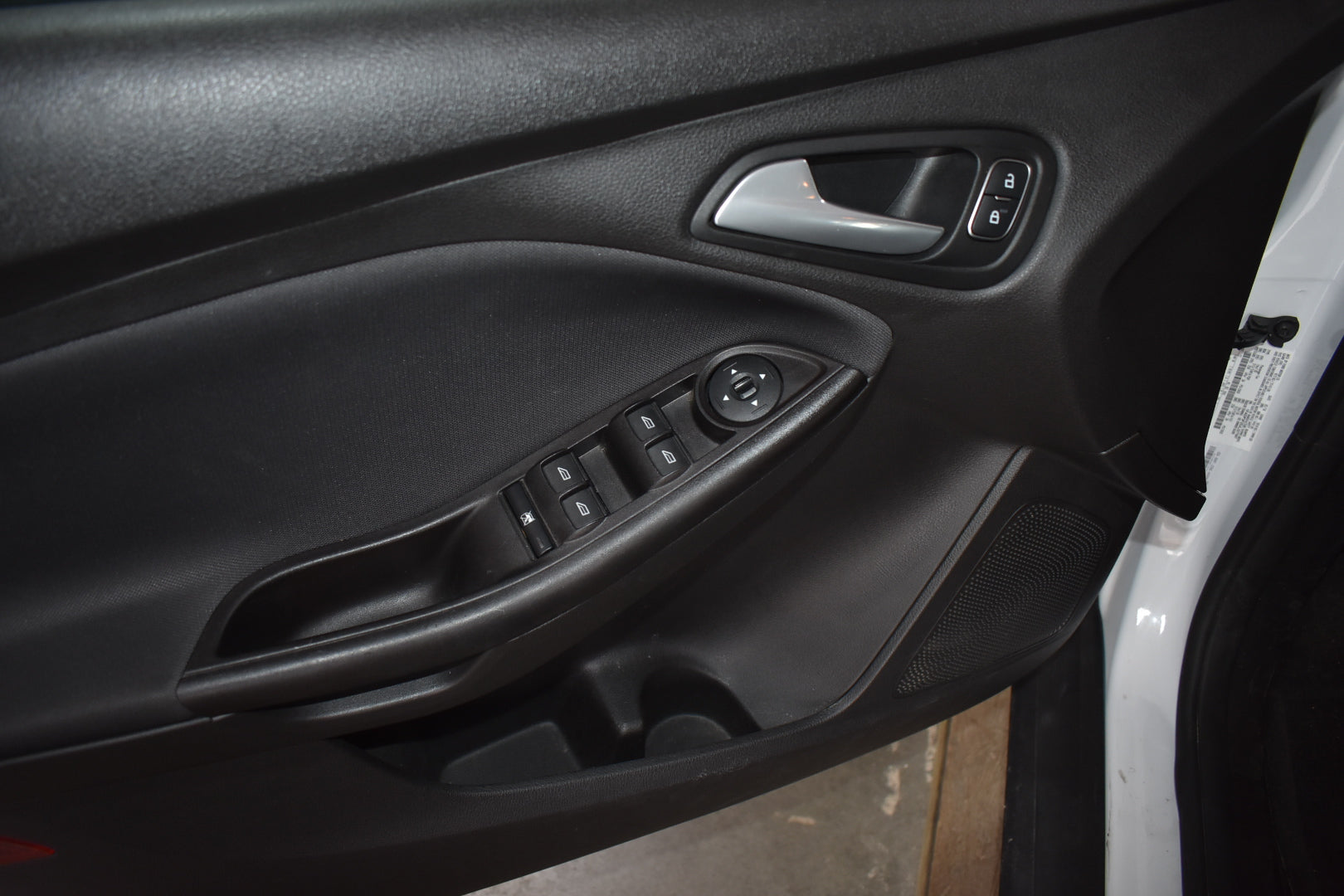 Close-up of a car door panel with controls and window switch.