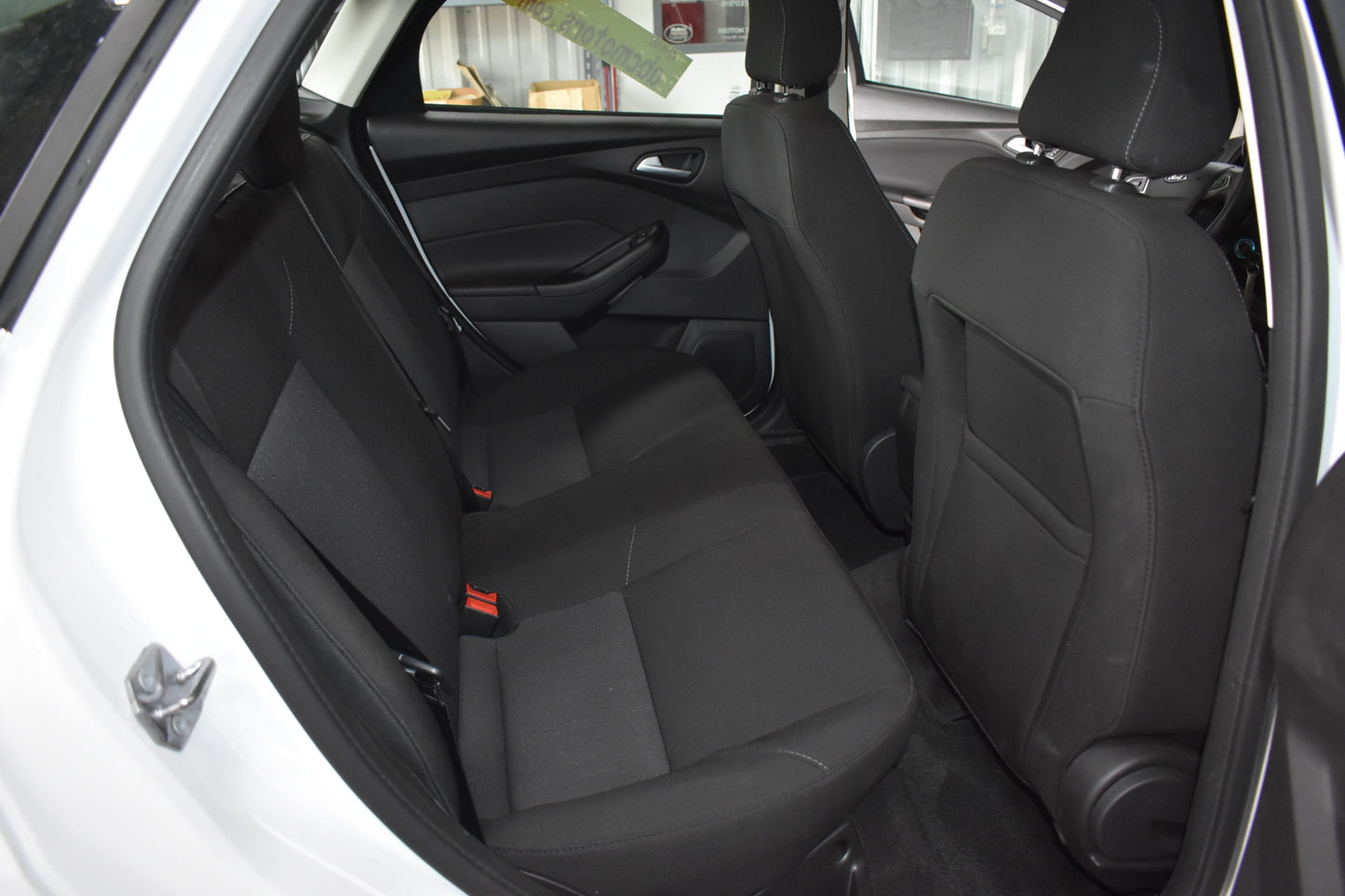 Back seat of a car with black seats and visible door open