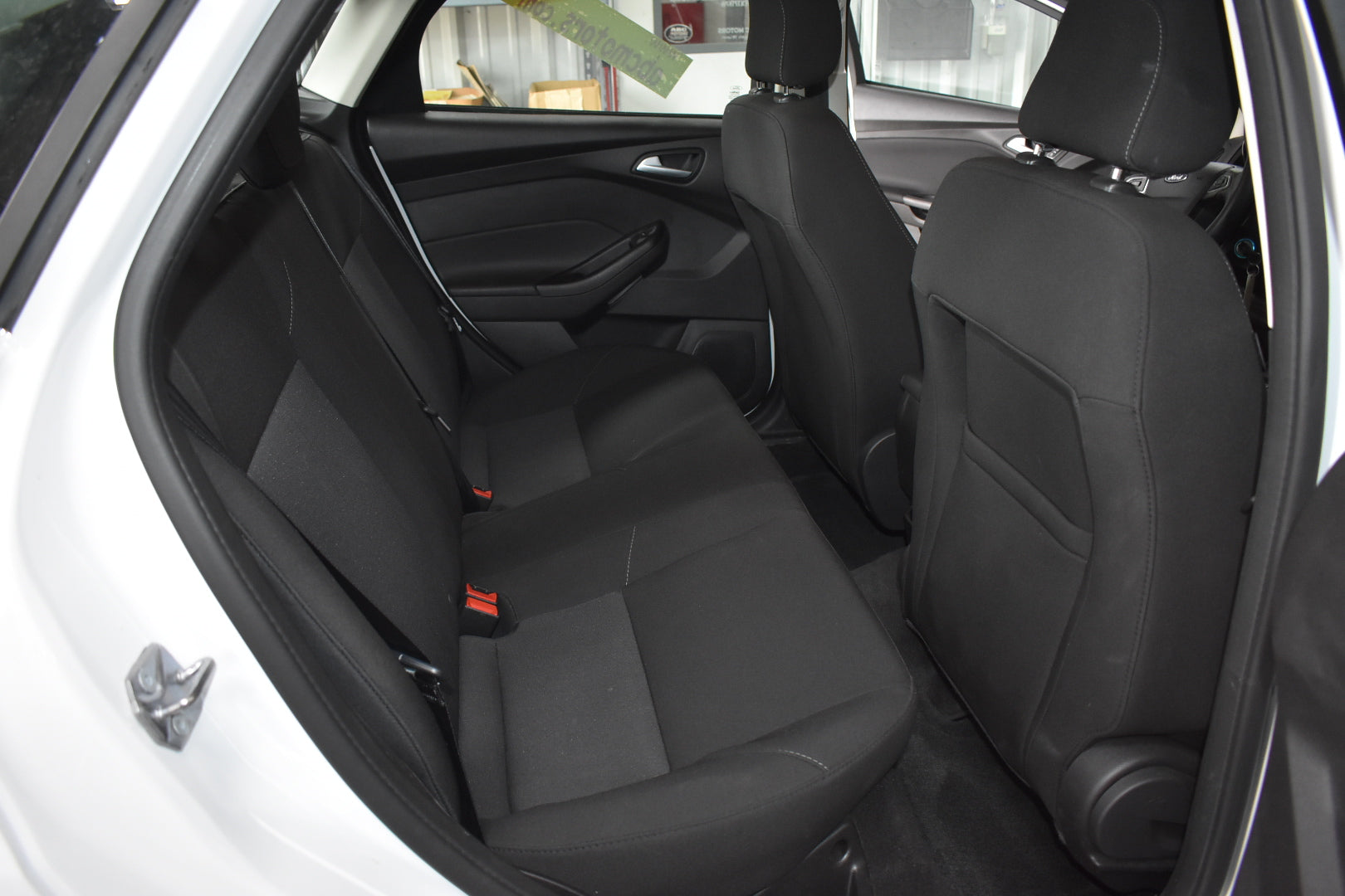 Back seat of a car with black seats and visible door open