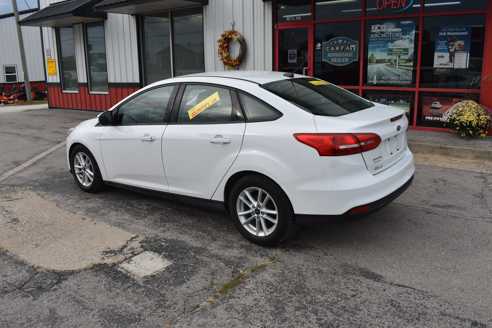 White car parked in front of a car dealership