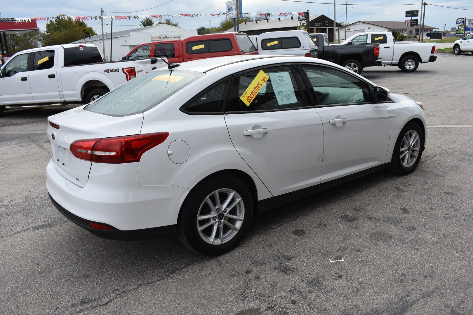 White car with sale signs in a used car lot
