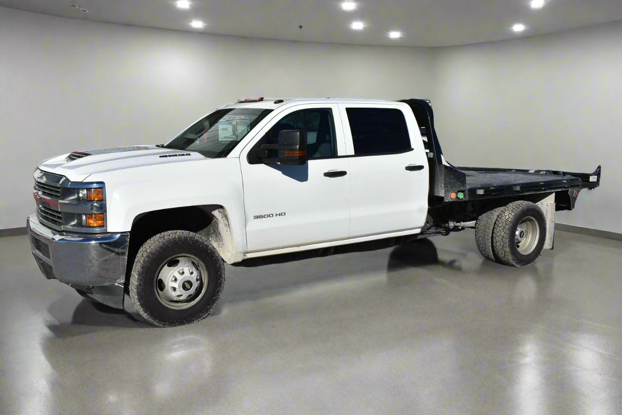 White pickup truck with a flatbed in front of a building with a sign that reads 'Carfax'.