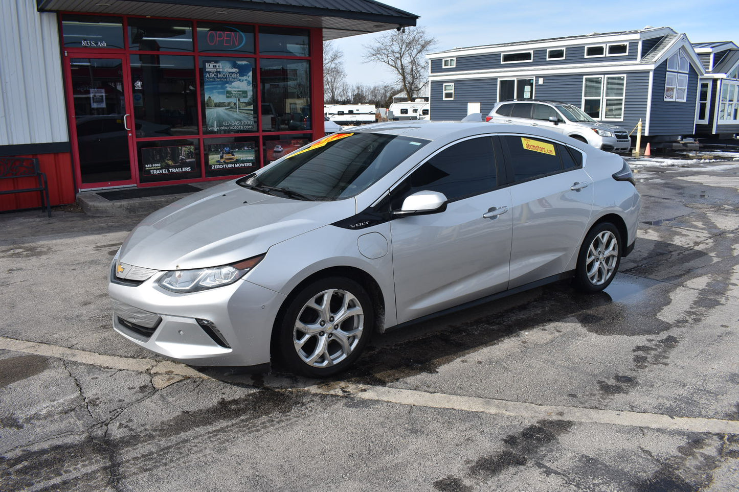 Silver car parked in front of a building with a red door